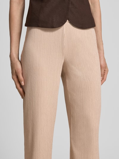 Kobieta nosi spodnie materiałowe o kroju relaxed fit, fakturowany wzór, elastyczny pas, model 'Filiz' od STEHMANN, zbliżenie na biodra. Szerokość w rozmiarze 36: 36 cm, długość wewnętrzna nogawki w rozmiarze 36: 73 cm.