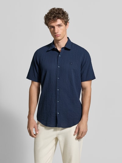 Männermodel trägt Relaxed Fit Freizeithemd mit Logo-Stitching und Kentkragen aus Seersucker von Lerros in Dunkelblau, Ganzkörperansicht von vorne. Rückenlänge bei Größe M: 75 cm, Schulterbreite 45 cm, Ärmellänge 25 cm, abgerundeter Saum, Knopfleiste.