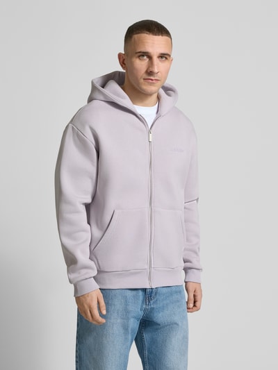 Männermodel trägt Sweatjacke mit Känguru-Tasche von REVIEW aus Baumwoll-Mix in Hellgrau, Relaxed Fit, Ganzkörperansicht von vorne.