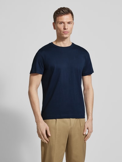 Männermodel trägt Regular Fit T-Shirt aus reiner Baumwolle von Tom Tailor, unifarben dunkelblau, Logo-Stitching, Nahaufnahme Oberkörper.