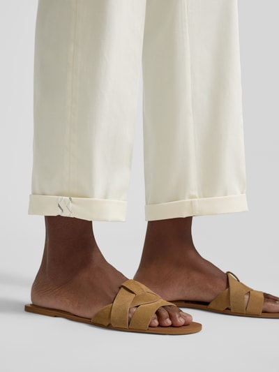Kobieta nosi Regular Fit Chino aus Baumwoll-Mix od s.Oliver BLACK LABEL, efekt: jednolity kolor, mieszanka bawełny, detale: wpuszczane kieszenie, szlufki na pasek, zakończenie nogawek z mankietem, zapięcie na guzik i zakryty zamek błyskawiczny, widok: zbliżenie na nogawki i stopy