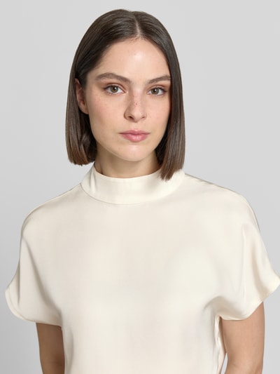 Frauenmodel trägt Damen Bluse Regular-Fit aus Acetat mit Stehkragen Modell 'Zarlia' von Someday, kurzärmelig, Nahaufnahme Oberkörper. Rückenlänge bei Größe 36: 53 cm, cremefarbene glatte Textur.