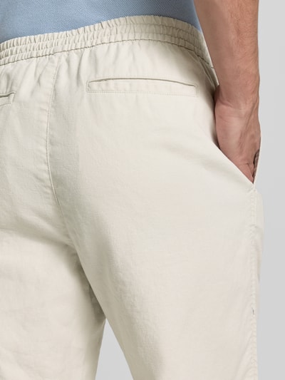 Mężczyzna nosi Leinenhose mit elastischem Bund und Eingrifftaschen od GAP, mieszanka lnu i bawełny, krój loose fit, wpuszczane kieszenie, elastyczny pas, kolor jasny beż, Długość wewnętrzna nogawki 80 cm, Szerokość w rozmiarze M 43 cm, detaliczny widok z tyłu