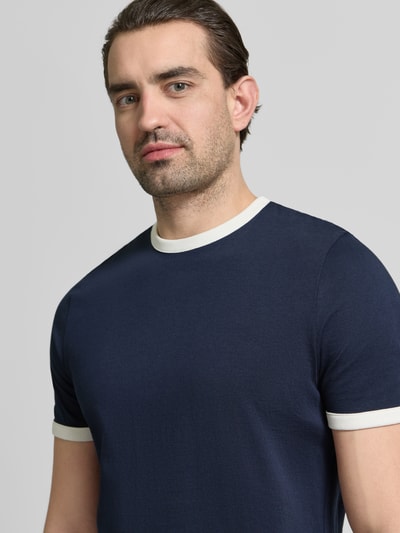 Männermodel trägt Slim Fit T-Shirt mit Rundhalsausschnitt von MCNEAL in Dunkelblau mit weißen Bündchen, reine Baumwolle, Nahaufnahme Oberkörper.