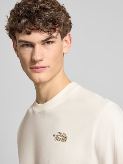Männermodel trägt Relaxed Fit T-Shirt aus reiner Baumwolle von The North Face, offwhite, label-print, ronde hals, relaxed fit, Nahaufnahme Oberkörper.