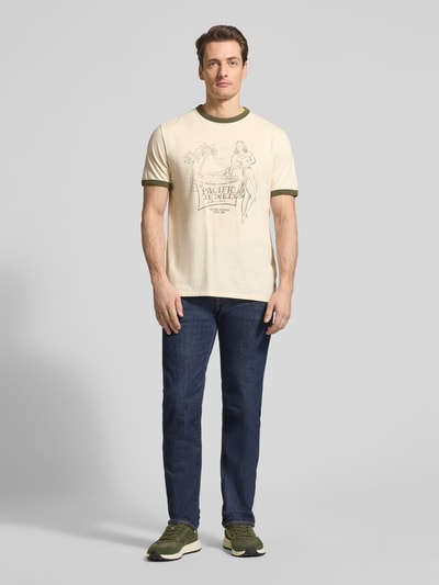 Männermodel draagt T-shirt met motiefprint Model 'NO PLAN TO LEAVE' van Guess, puur katoen, regular fit, ronde hals, ruglengte maat M 70 cm, Ganzkörperansicht van voren.