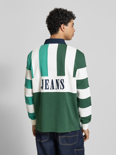 Männermodel trägt Relaxed Fit Poloshirt aus reiner Baumwolle von Tommy Jeans, Optik: mehrfarbig, Label-Schriftzug, Ganzkörperansicht Rückansicht.