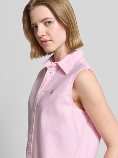 Vrouwenmodel draagt Relaxed Fit Hemdbluse aus reiner Baumwolle van Polo Ralph Lauren in lichtroze, oxford katoen, logo-stitching, zonder mouwen, eenrijige knoopsluiting, v-hals, uni look. Detailopname bovenlichaam.