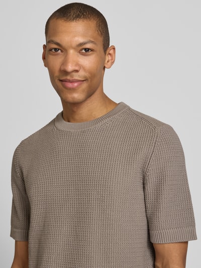 Männermodel trägt Relaxed Fit Strickpullover aus reiner Baumwolle Modell 'SAFFON' von HUGO, beige, Waffelstruktur, Nahaufnahme Oberkörper.