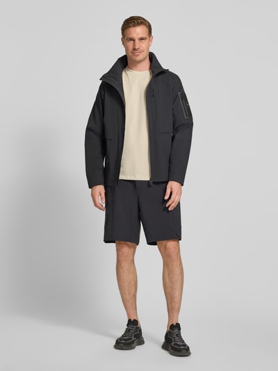 Männermodel trägt Relaxed Fit Cargoshorts mit Label-Schriftzug Modell 'GLOBE CARGO' von BOSS Green, unifarben, Ganzkörperansicht von vorne.