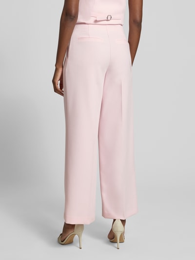 Frauenmodel trägt Wide Leg Hose mit Bügelfalten Modell 'Lee' von Forever New in zartrosa, glatter Stoff, Ganzkörperansicht Rückansicht. Material-Mix mit Viskose-Anteil, Bundweite bei Größe 36: 34 cm, Innenbeinlänge: 77 cm.