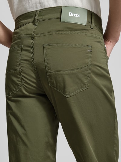 Männermodel trägt Slim Fit Stoffhose mit Lyocell-Anteil Modell 'Cadiz' von Brax in olivgrün, 5-pocket-design, detailaufnahme Rückansicht, elastische katoenmix, knoop- en ritssluiting, taillewijdte 107 cm, binnenbeenlengte 81 cm.