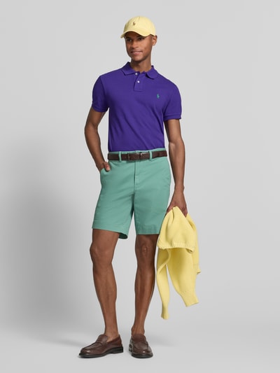 Männermodel trägt Straight Fit Chinoshorts aus katoenmix van Polo Ralph Lauren, look: effen, pasvorm: straight fit, logodetail, riemlussen, knoop- en ritssluiting, achterzakken, zij-steekzakken, materiaal: katoenmix, geheelopname voorkant.