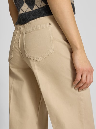 Kobiece model prezentuje Wide Fit Jeans mit Bügelfalten od Christian Berg Woman, beż, mieszanka bawełny, 5 kieszeni, kanty, zapięcie na guzik i zamek błyskawiczny, odpinana materiałowa tasiemka, szerokość w rozmiarze 36/32: 107 cm, długość wewnętrzna nogawki 77 cm, detaliczny widok tylnej części spodni, zbliżenie na biodra.