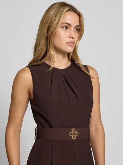 Frauenmodel trägt Jumpsuit mit Stoffgürtel von Rinascimento in Dunkelbraun mit Raffungen, glatter Textur, Nahaufnahme Oberkörper. Material-Mix mit Stretch-Anteil, taillierte Passform, Rundhalsausschnitt, ärmelloses Design.