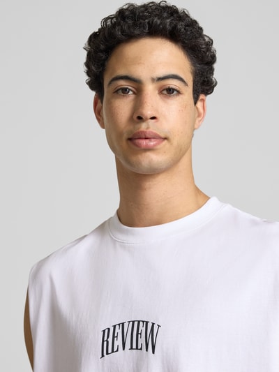 Männermodel trägt weißes Muskelshirt mit Logo und Rundhalsausschnitt von REVIEW, reine Baumwolle, Regular Fit, Nahaufnahme Oberkörper