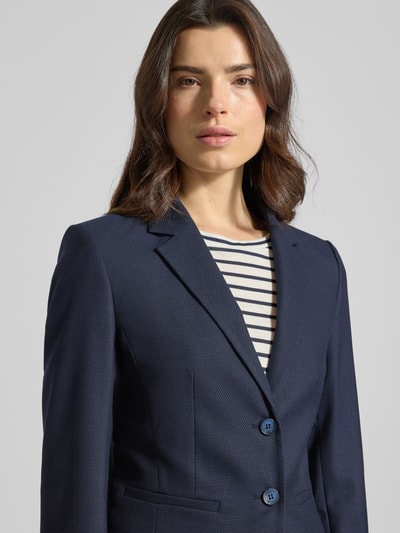 Frauenmodel trägt Slim Fit Blazer mit Reverskragen von More & More, dunkelblauer Material-Mix mit Viskose-Anteil, Nahaufnahme Oberkörper.