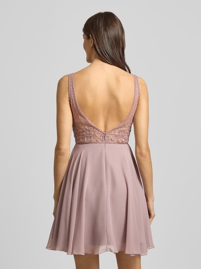 Frauenmodel trägt Regular fit Minikleid mit floralem Spitzenbesatz von Laona in semitransparenter Optik, Ziersteinbesatz, ärmelloses Design, blickdichter Unterrock, fließender Stoff in Rosé, Rückenlänge 63 cm bei Größe 36, Ganzkörperansicht Rückansicht.