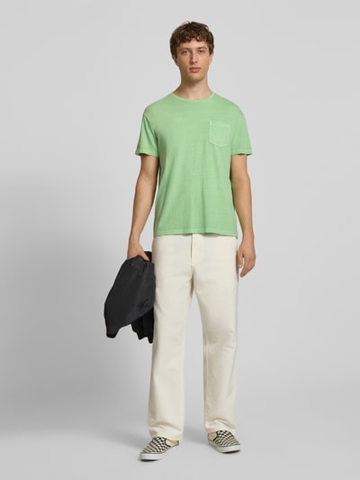 Männermodel trägt T-Shirt aus Baumwoll-Leinen-Mix mit Brusttasche von Superdry in Grün, Regular-Fit, Rundhalsausschnitt, Ganzkörperansicht von vorne, Rückenlänge bei Größe M 66 cm.