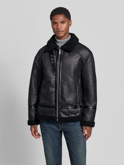 Männermodel trägt Regular Fit Jacke in Leder-Optik von Lindbergh in Schwarz mit Kunstfellbesatz und Umlegekragen, Ganzkörperansicht von vorne. Rückenlänge 74 cm, Schulterbreite 50 cm, Brustweite 47 cm, Ärmellänge 60 cm.