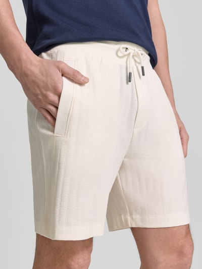 Mężczyzna nosi Regular Fit szorty z tunelem model 'JUANITO' od JOOP! kolekcja, bawełna, kremowy, szerokość w rozmiarze M: 43 cm, długość wewnętrzna nogawki: 17 cm, zbliżenie na górną część ciała.