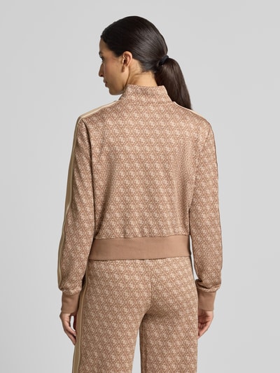 Frauenmodel trägt Regular Fit Sweatjacke mit Allover-Logo-Print von GUESS in Beige und Braun, elastischer Material-Mix, Stehkragen, elastische Abschlüsse, Ganzkörperansicht Rückansicht.
