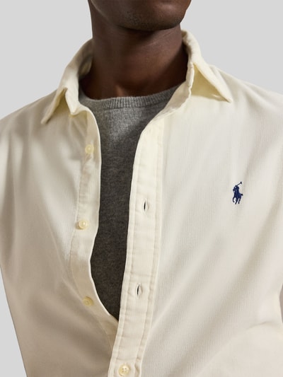 Männermodel trägt Custom Fit Freizeithemd aus reiner Baumwolle von Polo Ralph Lauren in Creme mit Knopfleiste, Nahaufnahme Oberkörper.