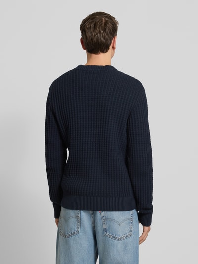 Männermodel trägt Regular Fit Strickpullover aus reiner Bio-Baumwolle Modell 'TOM' von SELECTED HOMME, donkerblauw, structuur, geheel effen, geribde boorden, lange mouwen, Ganzkörperansicht Rückansicht.
