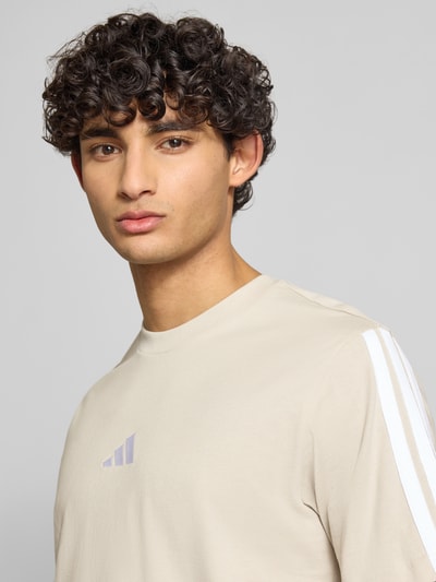 Männermodel trägt Regular Fit T-Shirt aus reiner Baumwolle von adidas Sportswear, Optik: Unifarben, Logo-Print, Kontraststreifen, Rundhals, Ärmelform: Kurzarm, Nahaufnahme Oberkörper.