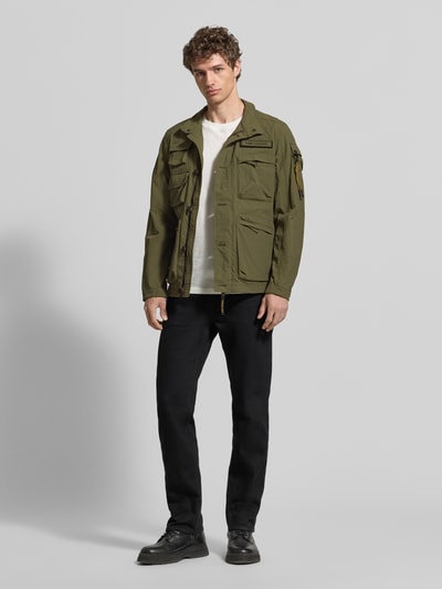 Męski model nosi Jacke mit Stehkragen und Cargotaschen Modell 'CARGOYET' od PME Legend, kolor oliwkowy, krój regular fit, z kieszeniami cargo, widok całej sylwetki z przodu. Szerokość w rozmiarze M: 58 cm, długość tyłu: 72 cm, szerokość ramion: 47 cm, długość rękawa: 67 cm.