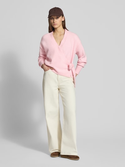 Frauenmodel trägt Regular Fit Cardigan mit Woll-Anteil Modell 'KIRA' von Only in Rosa, Strickoptik, Wickeloptik, Taillengürtel, Ganzkörperansicht von vorne.