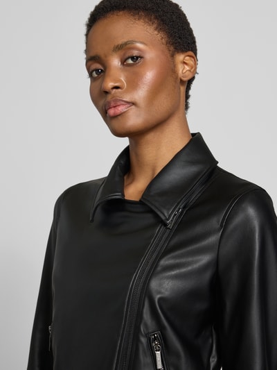 Frauenmodel trägt Jacke in Leder-Optik von Armani Exchange in Schwarz mit Reverskragen und Zweiwege-Reißverschluss, Nahaufnahme Oberkörper, taillierte Passform, Reißverschlusstaschen, Rückenlänge 57 cm, Schulterbreite 39 cm, Brustweite 47 cm, Ärmellänge 60 cm.