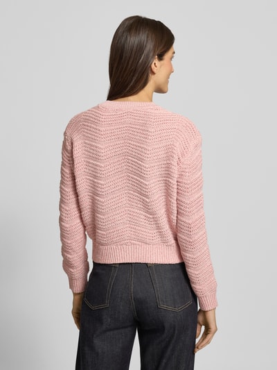 Frauenmodel trägt Strickpullover mit gerippten Abschlüssen von Guess in zartem Rosa, lockerer Schnitt, Rückenansicht, Ganzkörperansicht Rückansicht.