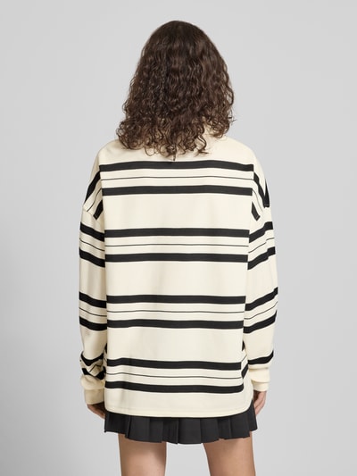Modelka nosi Oversized Polo-Langarmshirt mit Streifenmuster von Karo Kauer, mieszanka bawełny, wzór w paski, wyhaftowane logo, listwa guzikowa, długość tyłu w rozmiarze S: 71 cm, krój oversized. Ganzkörperansicht Rückansicht.