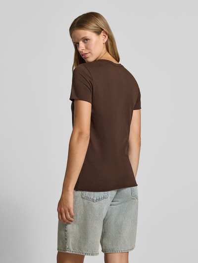 Frauenmodel trägt Regular Fit T-Shirt aus reiner Baumwolle 'ONLLUCY' von ONLY in Braun, kombiniert mit hellblauen Jeansshorts, Ganzkörperansicht Rückansicht. Damen T-Shirt von ONLY.