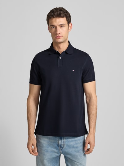 Mannenmodel draagt Regular Fit Poloshirt met Logo-Stitching van Tommy Hilfiger, donkerblauw katoen-elastaan, voorkant, halve lichaamsopname.