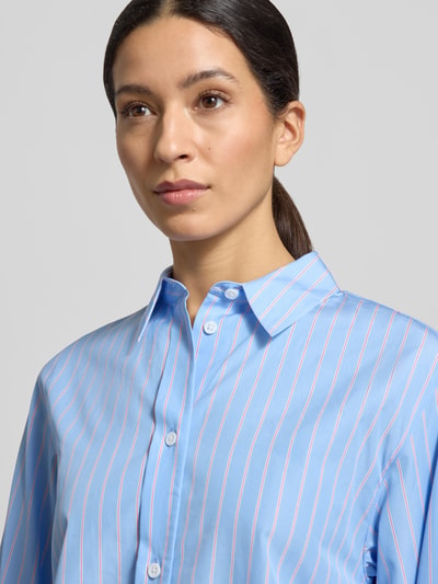Vrouwenmodel draagt 'Hemdbluse mit Knopfleiste' van Windsor in lichtblauw met fijne strepen, zuiver katoen, los model, detailopname bovenlichaam.
