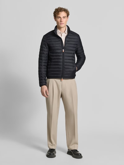 Mannenmodel draagt zwart gewatteerd jack met opstaande kraag, tweewegritssluiting, ritszakken, Model 'ALEXANDER' van Save The Duck, slim fit, maat M, ruglengte 67 cm, schouderbreedte 47 cm, borstwijdte 57 cm, mouwlengte 68 cm, geheel van voren.