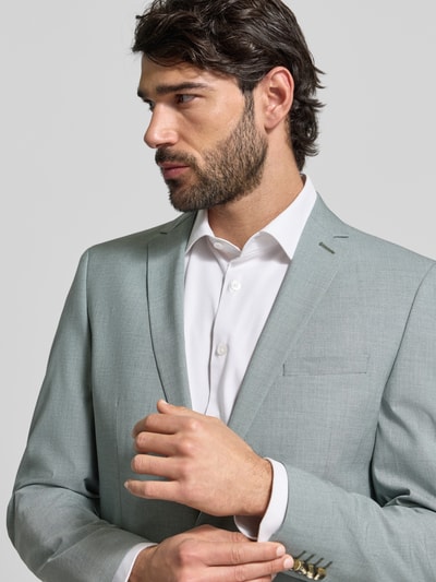 Męski model nosi Regular Fit Anzugsakko mit Viskose-Anteil od s.Oliver BLACK LABEL, melanż, kołnierz z połami, zapięcie na 2 guziki, kieszenie z patką, brustasza, kieszeń wewnętrzna, krój regular fit, mieszanka z wiskozą, długi rękaw, nachodzące na siebie guziki. Zbliżenie na górną część ciała z przodu.