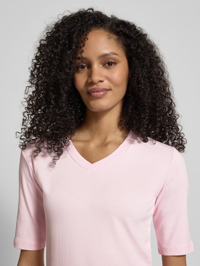Kobiece model nosi T-shirt mit V-Ausschnitt od Christian Berg Woman z mieszanki bawełny i elastanu, krój regular fit, rękaw o dł. 1/2, długość tyłu w rozmiarze S: 55 cm, jasnoróżowy, gładka faktura, zbliżenie na górną część ciała