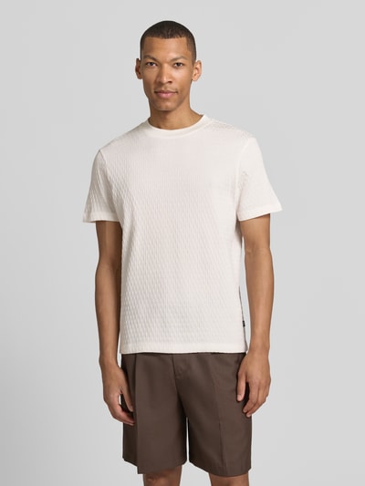 Mężczyznamodel nosi T-Shirt mit Strukturmuster Modell 'Raulos' von JOOP! Collection, biała bawełna, krój modern fit, okrągły dekolt, widoczne detale marki, teksturowana powierzchnia, przód z widoku całej sylwetki.