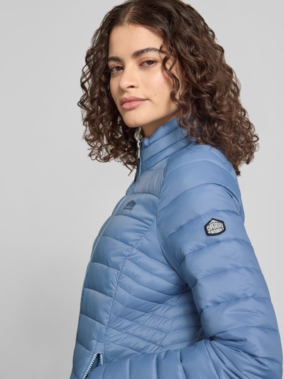 Kobiece model prezentuje jasnoniebieską Steppjacke mit Logo-Stitching Modell 'FUJI' od Superdry, stójka, boczne kieszenie, detaliczne ujęcie górnej części ciała.