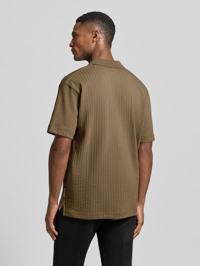 Männermodel trägt Relaxed Fit Poloshirt aus reiner Baumwolle von Marc O'Polo in strukturiertem Uni-Braun, Rückansicht Ganzkörperansicht.