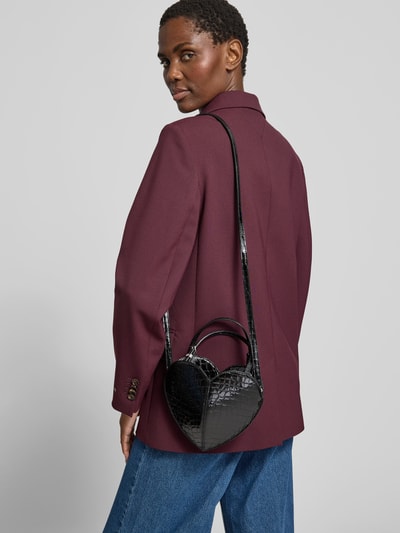 Frauenmodel trägt Crossbody Bag aus echtem Leder von ROTATE mit Schlangenmuster, schwarzer Glanzoptik, kurzer Tragehenkel, Hauptfach mit Zipper, schmaler Schulterriemen, Ganzkörperansicht Rückansicht.
