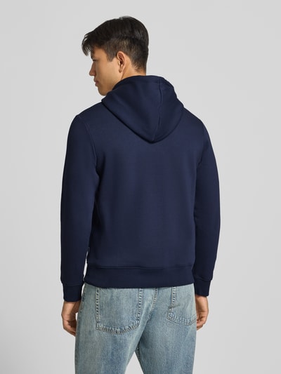 Männermodel trägt Relaxed Fit Hoodie aus Baumwoll-Mix Modell 'KYLE' von JACK & JONES in Dunkelblau mit Kapuze, Ganzkörperansicht Rückansicht. Herren Hoodie, Rückenlänge 67 cm, Ärmel 65 cm, Känguru-Tasche, Label-Detail.