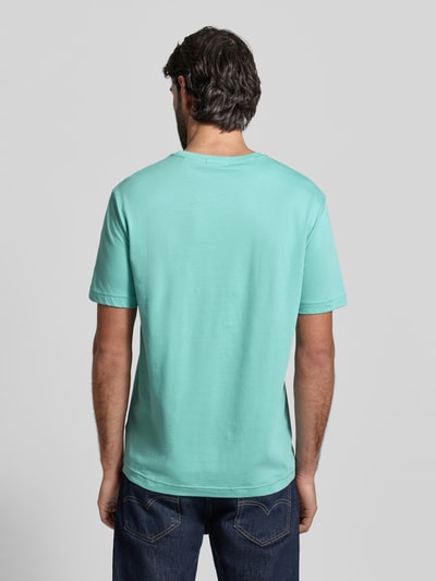 Męski model nosi Regular Fit T-Shirt mit Logo-Stitching od Gant, czysta bawełna, krój regular fit, kolor miętowy, widok całej sylwetki od tyłu.