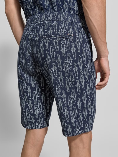 Männermodel trägt Chino Shorts mit französischen Eingrifftaschen von Lerros in Blau mit Fischmuster, Baumwoll-Mix, Ganzkörperansicht Rückansicht.