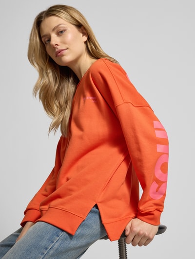 Modelka nosi Oversized Sweatshirt mit Label-Print od Smith and Soul w kolorze pomarańczowym, bawełniano-modalowy, nadruk, widok z przodu, zbliżenie górnej części ciała.