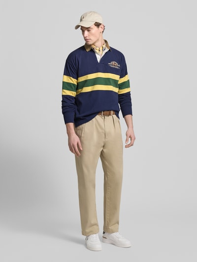 Männermodel trägt Sweatshirt mit gerippten Ärmelabschlüssen van Polo Ralph Lauren in blauw met gele en groene strepen, puur katoen, regular fit, polokraag, korte knoopsluiting, labelstitching; ruglengte maat M 68 cm, mouwlengte 62 cm, ganzkörperansicht van voren.