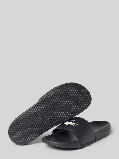 Produktfoto, Badeschuhe mit Logo Print Modell 'SERVE SLIDE' von Lacoste in Schwarz, Optik: Unifarben, Schuhspitze: Abgerundet, Absatzform: Flach, Applikation: Logo-Print, Verschluss: Schlupf/offen, Sohle: Strukturiert